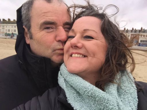 A man kissing his wife on the cheek on a windy beach