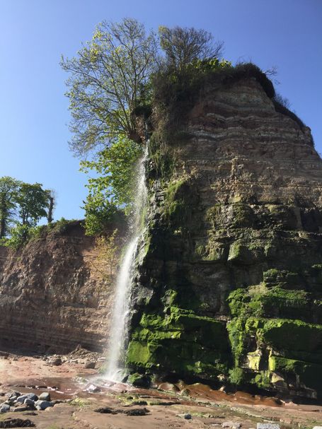 A waterfall from the cliffs above and onto a beach